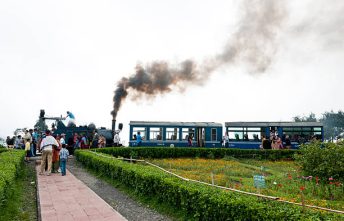 Batasia, Darjeeling, India - May 18th, 2012: Steam engine Toy Train has just stopped at the Batasia War Memorial in Darjeeling District(West Bengal); people sitting in the trainn and walking in the park.